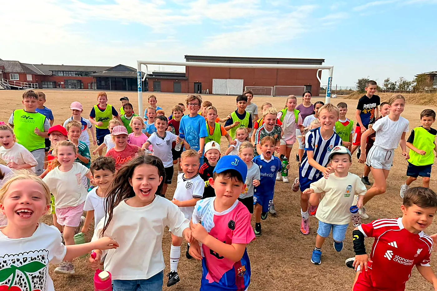 Children running towards the camera at a summer holiday football camp